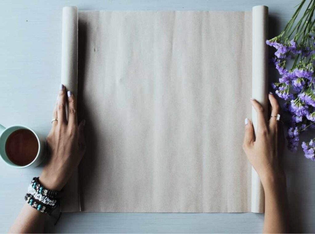 Hands preparing a blank paper with flowers and coffee – symbolizing goal setting and leadership mindset by Andreia Fernandes.