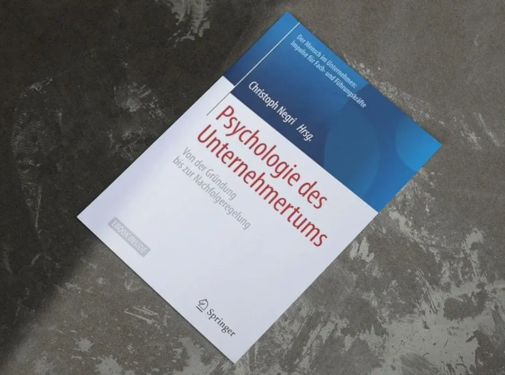Book cover of the Springer publication Psychologie des Unternehmertums by Christoph Negri, featuring the subtitle Von der Gründung bis zur Nachfolgeregelung. The book lies on a gray concrete surface and includes the Springer logo and an 'EBOOK INSIDE' label. Andreia Fernandes, keynote speaker and expert on leadership and failure culture, contributed a full chapter to this book, introducing her original framework 'The Dinosaur Principle' – a practical methodology for navigating failure and fostering resilience in entrepreneurial and team contexts